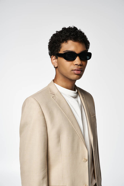 Όμορφος νεαρός άνδρας αποπνέει κομψότητα σε μαύρο κοστούμι και μοντέρνα γυαλιά ηλίου. - Φωτογραφία, εικόνα
