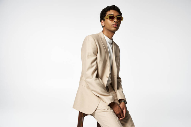 Handsome man in tan suit and sunglasses sits on stool. - Photo, Image