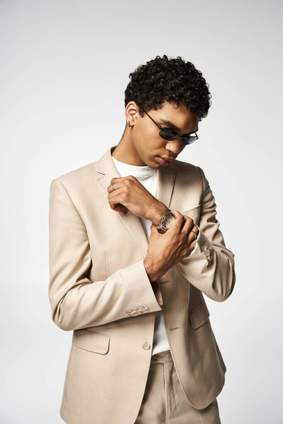 Beau Afro-Américain en costume bronzé et des lunettes de soleil élégantes ajuster sa montre. - Photo, image