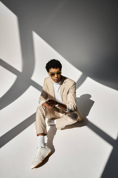 Bello uomo afroamericano in abito beige si siede con stile sul pavimento. - Foto, immagini