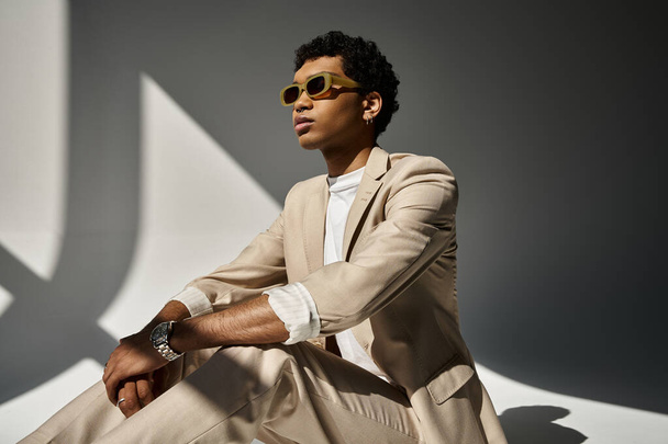 Handsome African American man sitting stylishly in beige suit and sunglasses. - Photo, Image