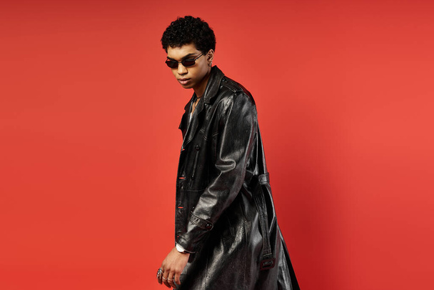 African American man in black trench coat on vibrant red backdrop. - Photo, Image