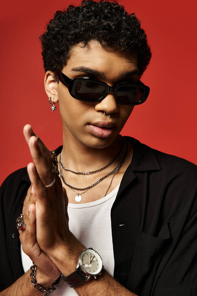 Junger Afroamerikaner in schwarzem Hemd trägt selbstbewusst Sonnenbrille. - Foto, Bild