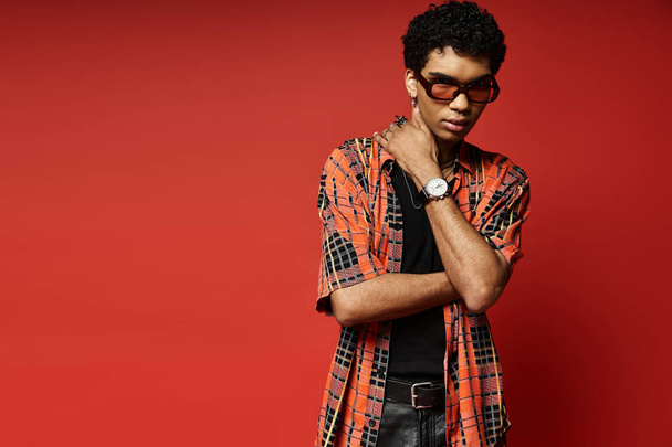 Bello afroamericano uomo indossare occhiali da sole contro audace sfondo rosso. - Foto, immagini