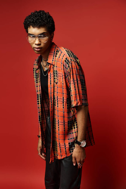 Homme afro-américain élégant en chemise rouge pose sur fond rouge vif. - Photo, image