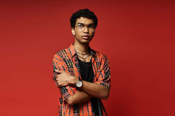 Handsome young man posing confidently in plaid shirt against vibrant red backdrop. - Photo, Image