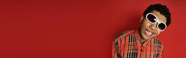 Komea Afrikkalainen Amerikkalainen mies yllään tyylikäs aurinkolasit punaisella taustalla. - Valokuva, kuva