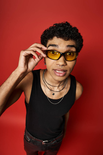 Afroamerikaner mit stylischer Sonnenbrille auf leuchtend rotem Hintergrund. - Foto, Bild