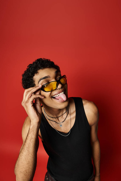 Güneş gözlüklü yakışıklı Afro-Amerikan adam, şakacı bir şekilde dilini uzatıyor.. - Fotoğraf, Görsel