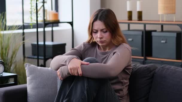 Reménytelenség és melankolikus kaukázusi fiatal nő depresszióban ül a kanapén az otthoni nappaliban. A válásból vagy magányból eredő érzelmi stressz. - Felvétel, videó