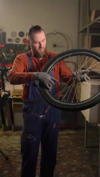 Концепция обслуживания велосипедов. Механический человек фиксирует и проверяет колесо велосипеда в веломастерской. Ремонтник монтажа и обслуживания велосипедов в гараже. Вертикальное видео - Кадры, видео