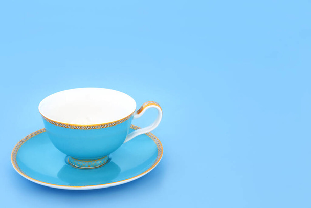 Blue and gold bone china tea cup. Elegant luxury drinking set on pastel blue background with copy space. Minimal zen composition. - Photo, Image