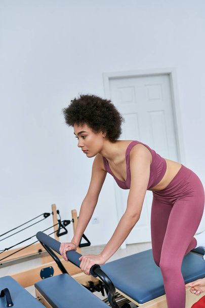 Una mujer se centra en su entrenamiento de remo en un gimnasio ocupado. - Foto, Imagen