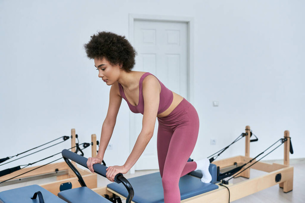 Pembe bluzlu bir kadın kürek makinesinde egzersiz yapıyor.. - Fotoğraf, Görsel