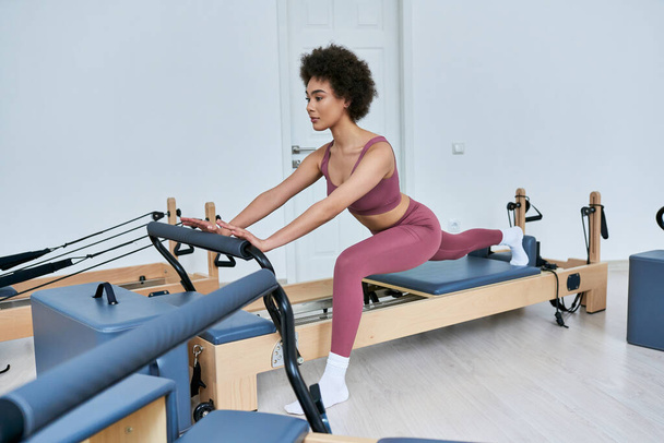 Fit Frau in rosa Sport-BH und Leggings beim Training an einem stationären Gerät. - Foto, Bild