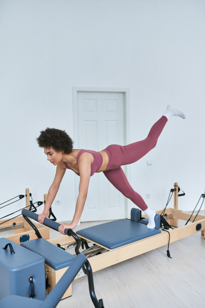 African American woman in pink, rowing machine workout. - Foto, imagen