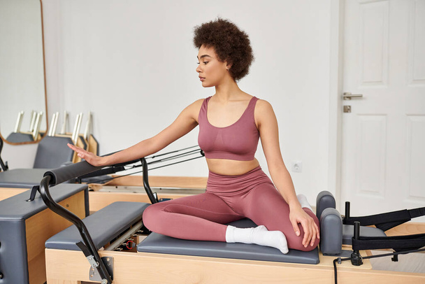 Woman practicing pilates seated on a mat in a peaceful class setting. - Photo, Image