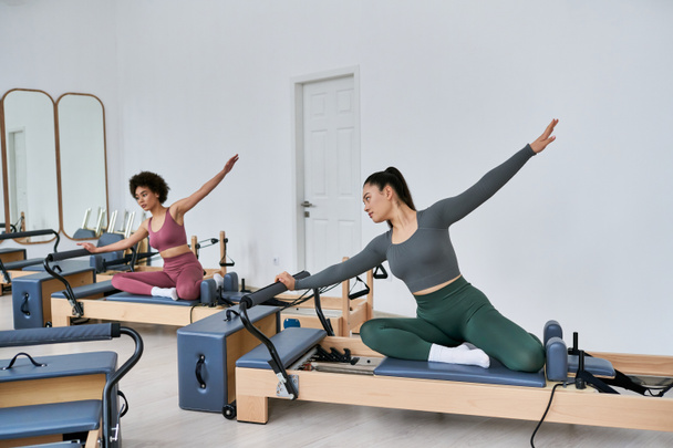Two women gracefully execute exercises in a gym setting. - Valokuva, kuva