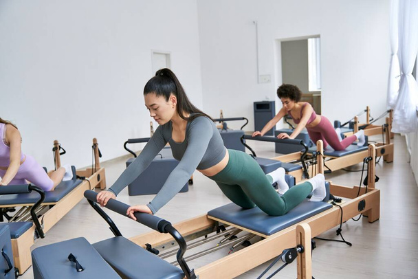 Women engage in pilates class, focusing on core strength and flexibility. - Foto, Bild