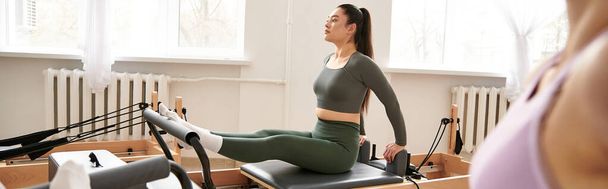 Woman in pilates pose in sportswear next to her friend. - Фото, зображення