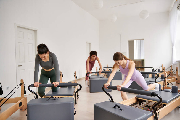 Egy csapat stílusos, sportos nő együtt edz egy dinamikus pilates edzésen.. - Fotó, kép