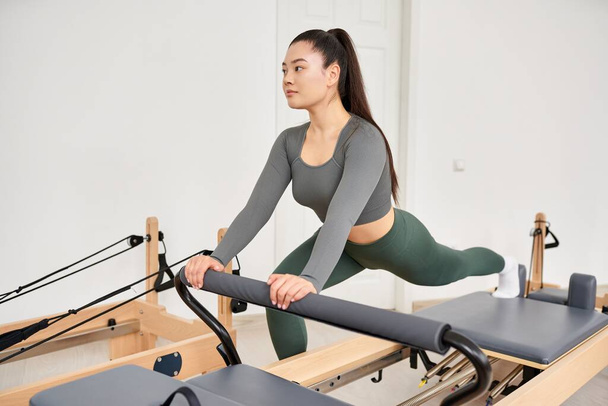 A sporty woman in gray shirt, green pants on Pilates lesson. - Foto, immagini