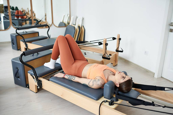 A pretty, sporty woman gracefully practicing pilates in a gym. - Photo, Image