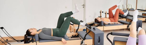 Δελεάζοντας τις γυναίκες που συμμετέχουν σε ένα pilates προπόνηση στο γυμναστήριο. - Φωτογραφία, εικόνα