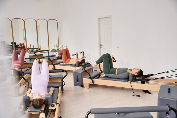 Group of sporty women performing synchronized exercises during a pilates lesson. - Photo, Image