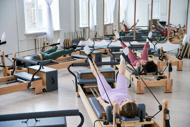 Eine Gruppe ziemlich sportlicher Frauen übt Pilates in einem Fitnessstudio. - Foto, Bild