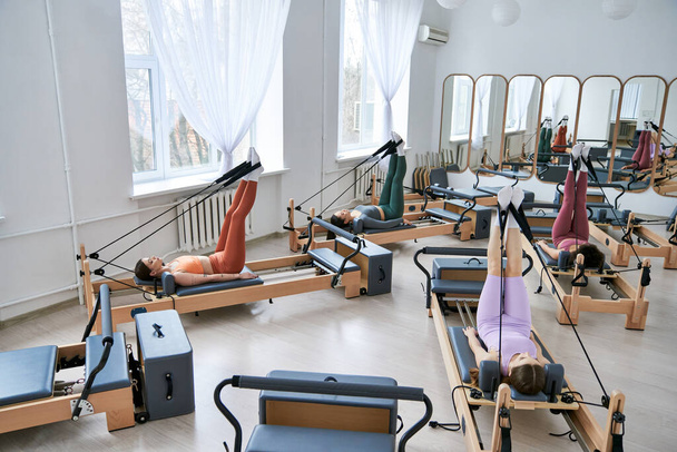 Group of women engaging in various exercises at the gym, particularly focusing on pilates. - Foto, Imagem