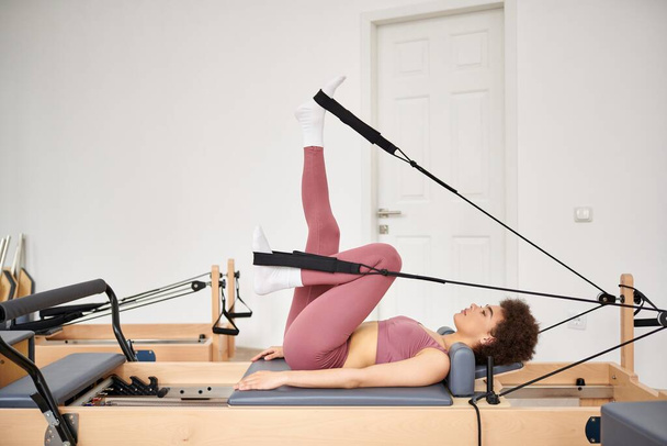 Donna sportiva in body rosa pratica esercizi di pilates. - Foto, immagini