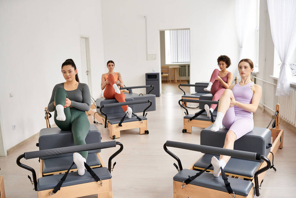 Un gruppo di donne sportive che praticano il pilates in una stanza, sedute sulle sedie. - Foto, immagini