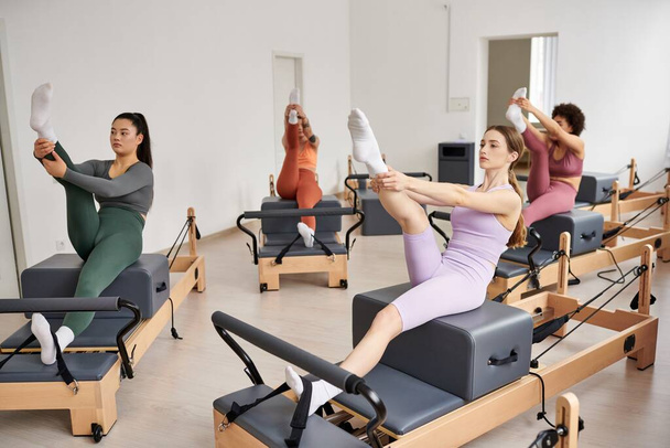 Athletic women gracefully exercising during a Pilates session in a gym. - Photo, image