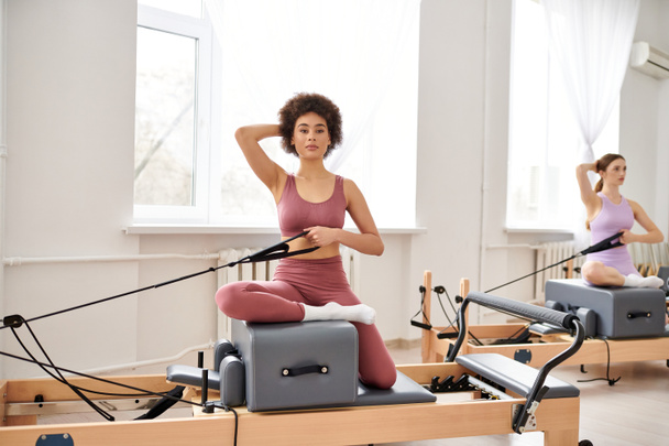Attractive women engage in a pilates class, focusing on flexibility and core strength. - Zdjęcie, obraz