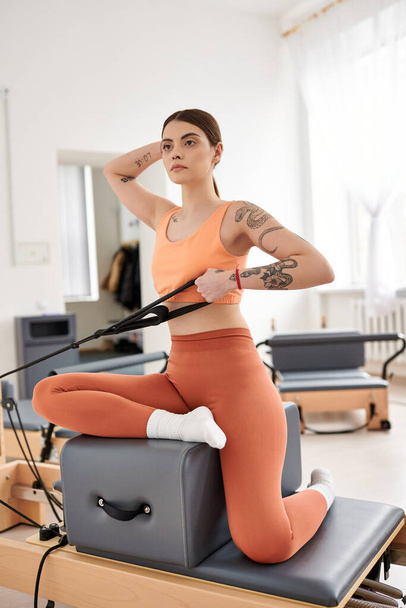 Jolie femme en haut orange et leggings pendant la session pilates. - Photo, image