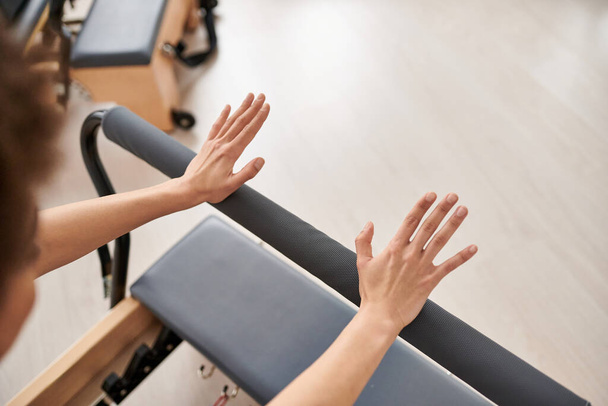 Hezká, sportovní žena natahuje paže na vybavení během lekce Pilates. - Fotografie, Obrázek