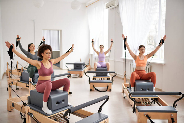 Un grupo de mujeres deportistas ejecutando con gracia ejercicios durante una lección de Pilates en el gimnasio. - Foto, Imagen