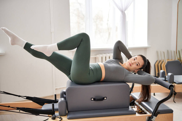 Mujer atractiva en ropa deportiva cómoda practicando durante la lección de pilates. - Foto, Imagen