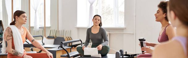 Aansprekende vrouwen nemen pauze tijdens pilates les in gym. - Foto, afbeelding