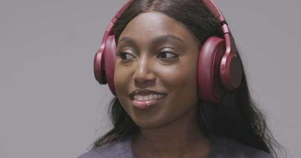Questa clip coinvolgente presenta una gioiosa donna afroamericana con le cuffie rosa. Appare immersa in una piacevole esperienza uditiva, magari ascoltando la sua musica preferita. I suoi sorrisi e - Filmati, video