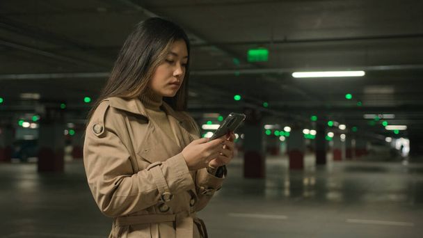 Zakenvrouw Aziatisch chinees japans vrouw vrouwelijk klant koreaans etnisch dame klant bestuurder staan op auto parkeren gebruik mobiel telefoon boeken taxi auto met smartphone app zoeken internet in ondergrondse - Foto, afbeelding