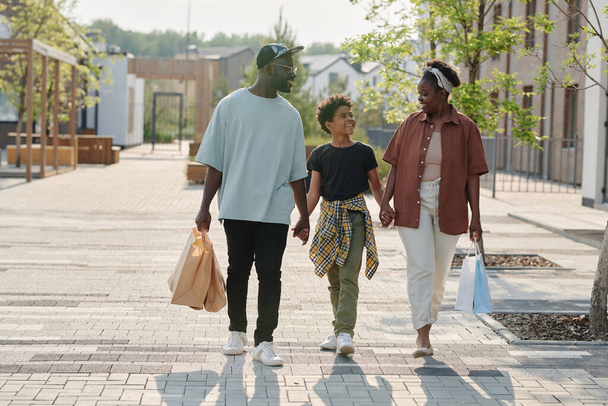 Familia feliz con niño caminando por la ciudad después de ir de compras - Foto, imagen