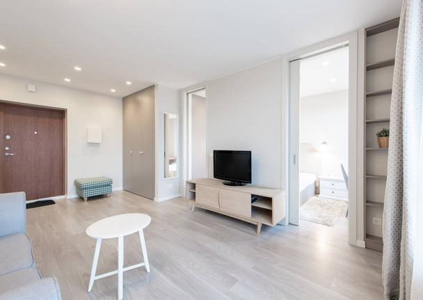 Moderno soggiorno interno con zona TV aperta e TV sulla scrivania in legno, divano e tavolino. - Foto, immagini