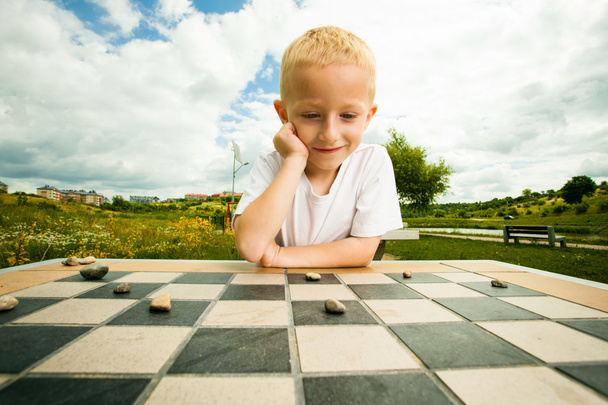 Child playing draughts or checkers board game outdoor - 写真・画像