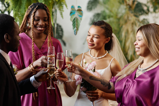 Porträt einer Gruppe von Freunden, die bei einem Hochzeitsempfang mit Champagnergläsern feiern und anstoßen - Foto, Bild
