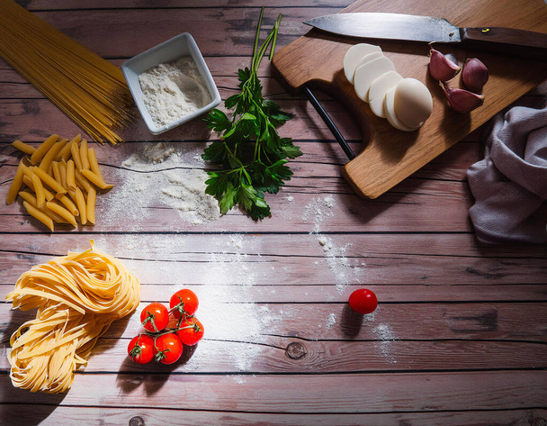  ingredienti per fare la pasta, farina, su un tagliere di legno  - Foto, imagen