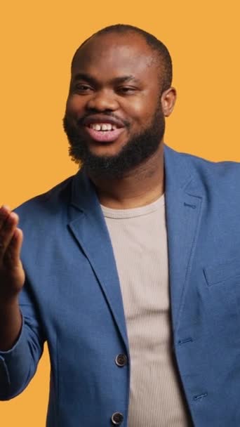 Vertical video Frisky playful african american man blowing kisses to camera, being flirty. Lively charming BIPOC person having fun sending air kisses, doing romantic gesturing, studio background - Footage, Video