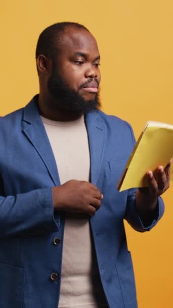 Video vertical Orador afroamericano leyendo libro en voz alta, narrando historia para el público. BIPOC persona que presenta novela literaria, recitación de páginas, espectadores entretenidos, fondo de estudio - Metraje, vídeo