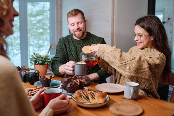 branco teen menina derramando chá no caneca para ela pai durante família refeição no campo casa - Foto, Imagem